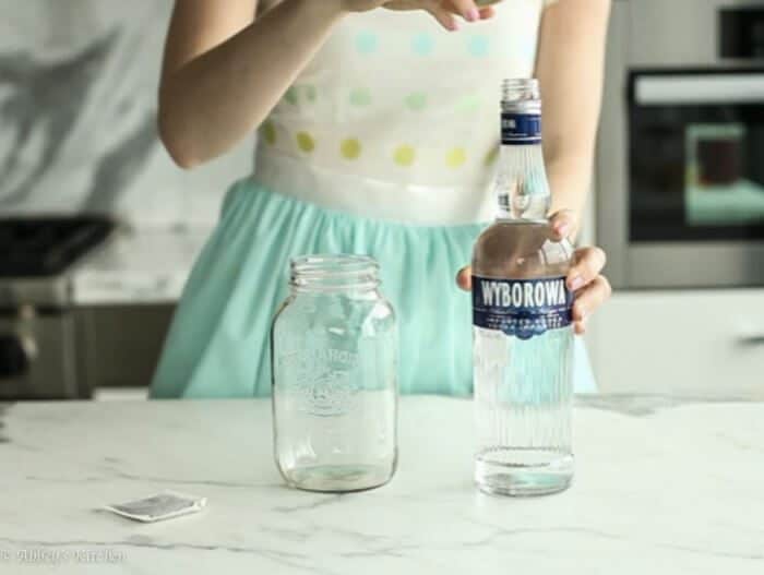 Abbey Sharp opening a bottle of vodka with a mason jar beside it.