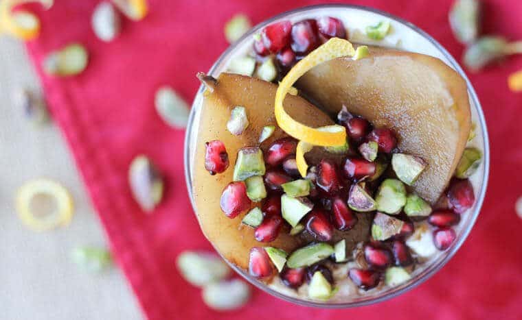 An overhead photo of poached pear overtop yogurt with pomegranate perils and pistachios sprinkled over top.