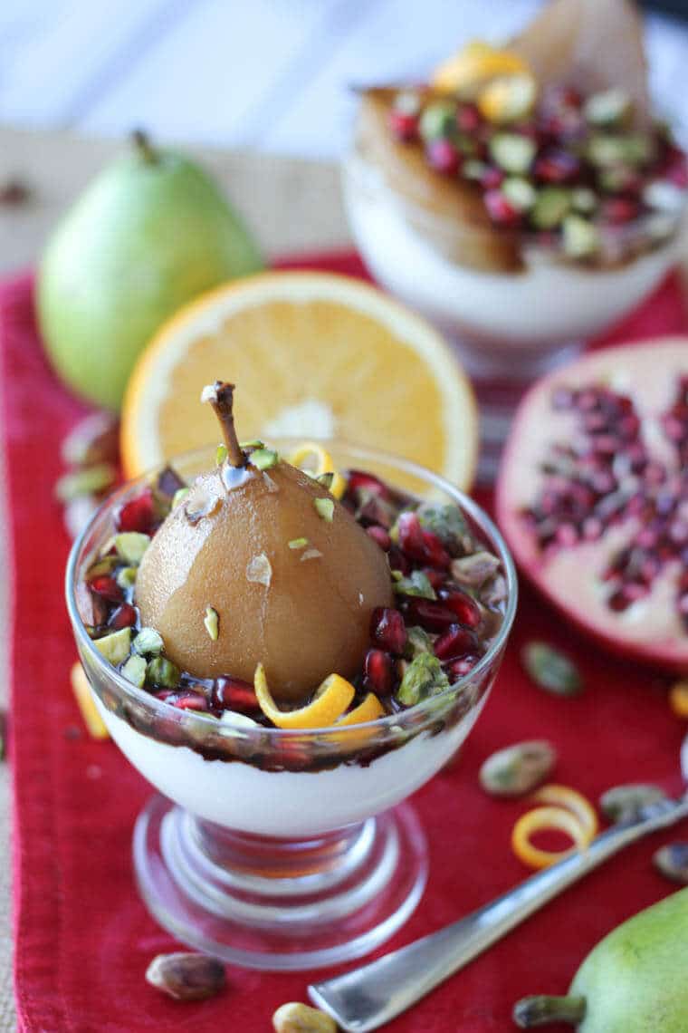A serving of poached pear with citrus and pomegranate in the background.