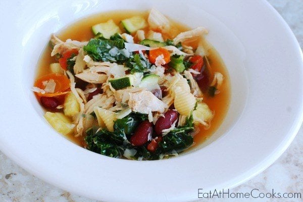 A white bowl with minestrone soup with chicken.