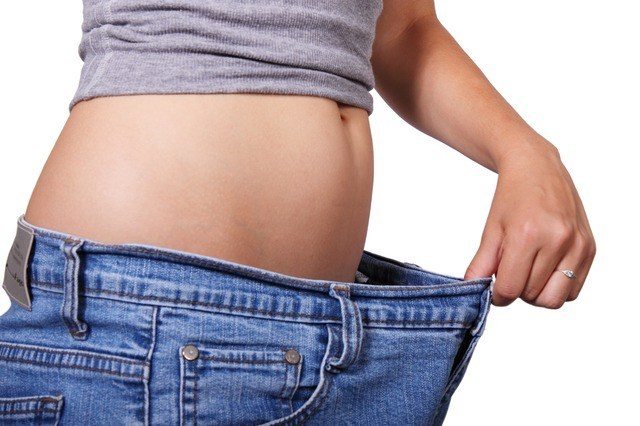 A person in a pair of large pants showing weight loss.