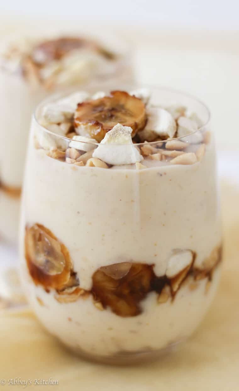 A close up photo of a glass of banana protein pudding recipe with banana garnished on top.