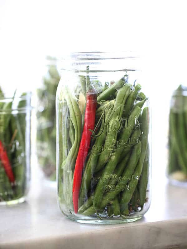 A mason jar with beans and a red chili pepper.