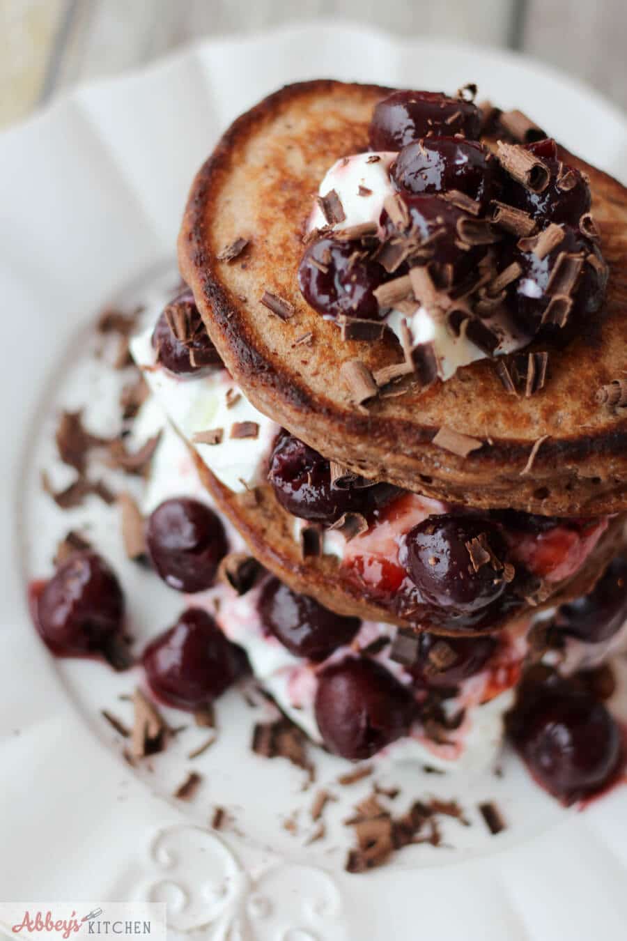 close up of black forest protein pancakes with whipped cream, cherries, and shaved chocolate