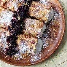 An overhead photo of a plate of three cheesecake stuffed french toast crepes.