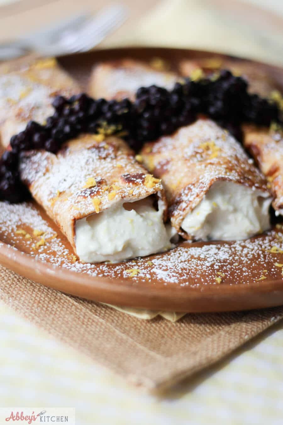 A close up a plate of cheesecake stuffed french toast crepes.