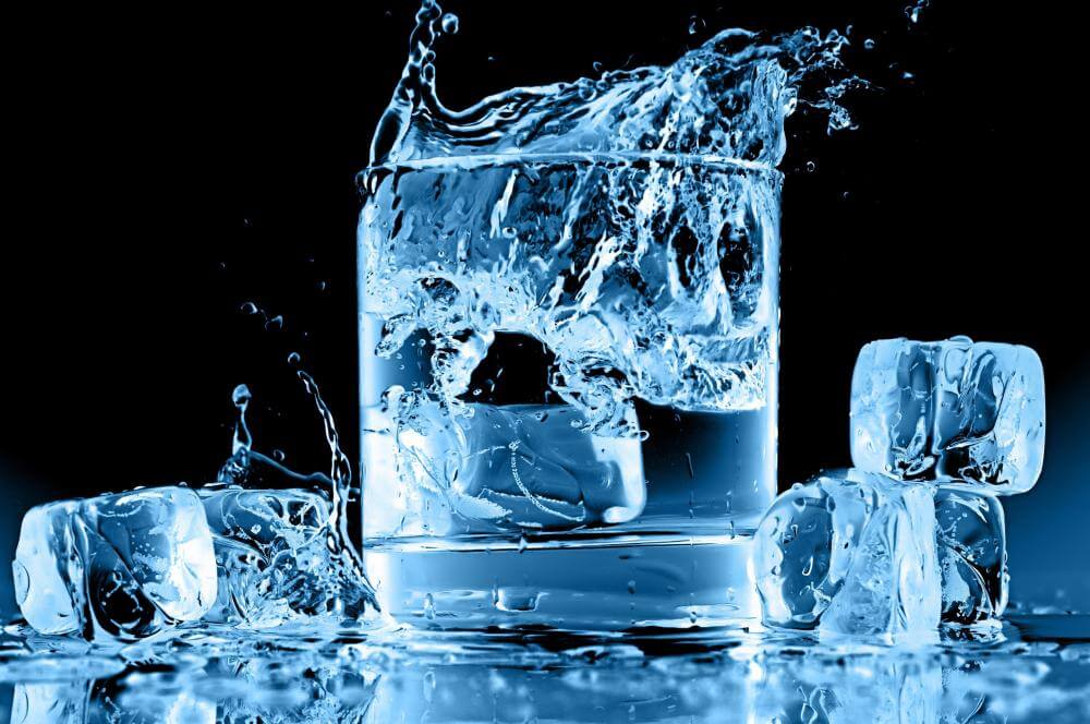 A glass of water with ice splashing in.