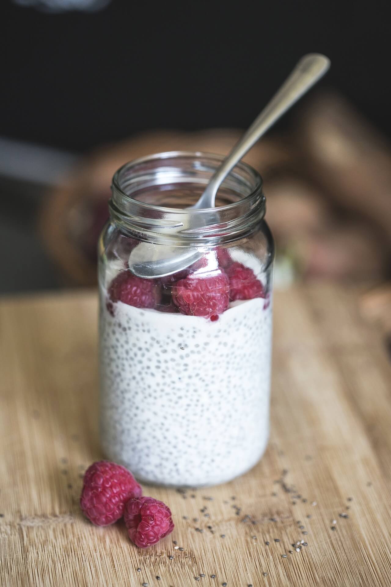 A jar of chia pudding with raspberries.