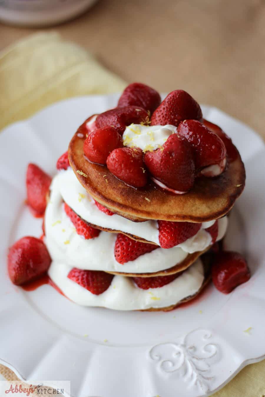 An overhead photo of a stack of cheesecake protein pancakes with strawberries on top.