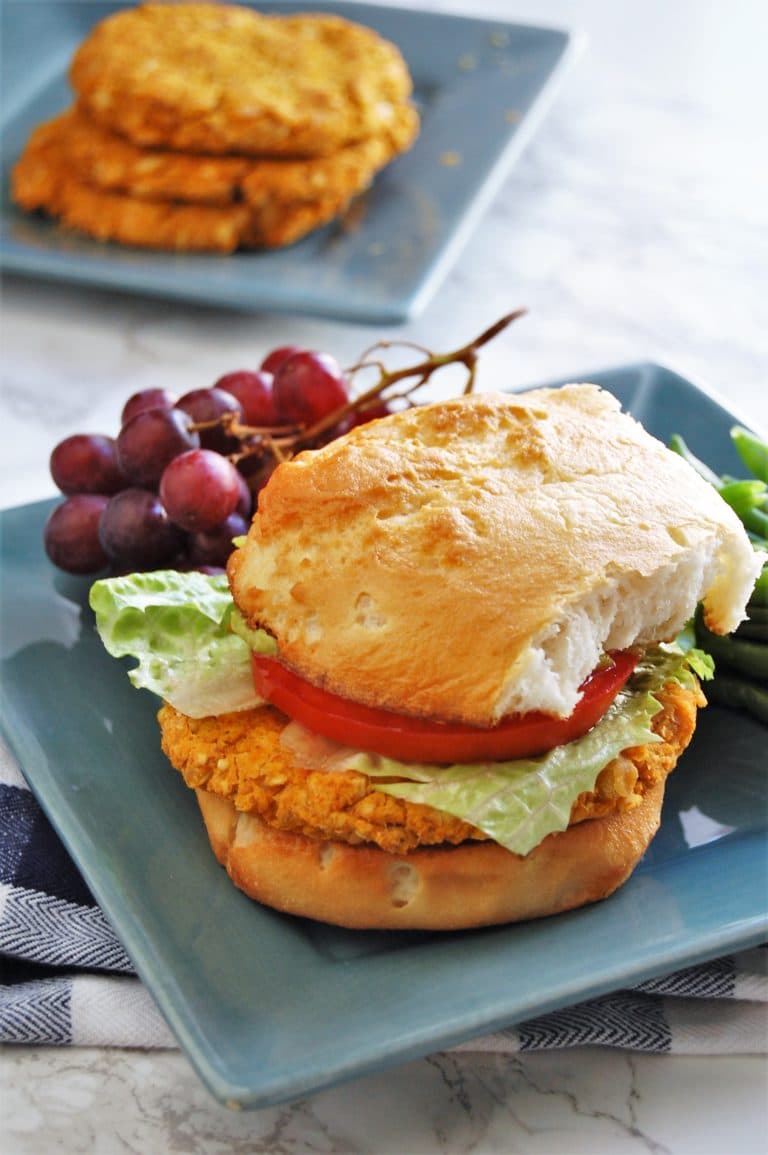 A sandwich on a blue plate with grapes alongside.