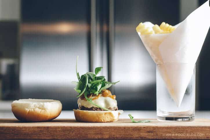 A arugula smoked mozzarella slider being assembled on a cutting board.