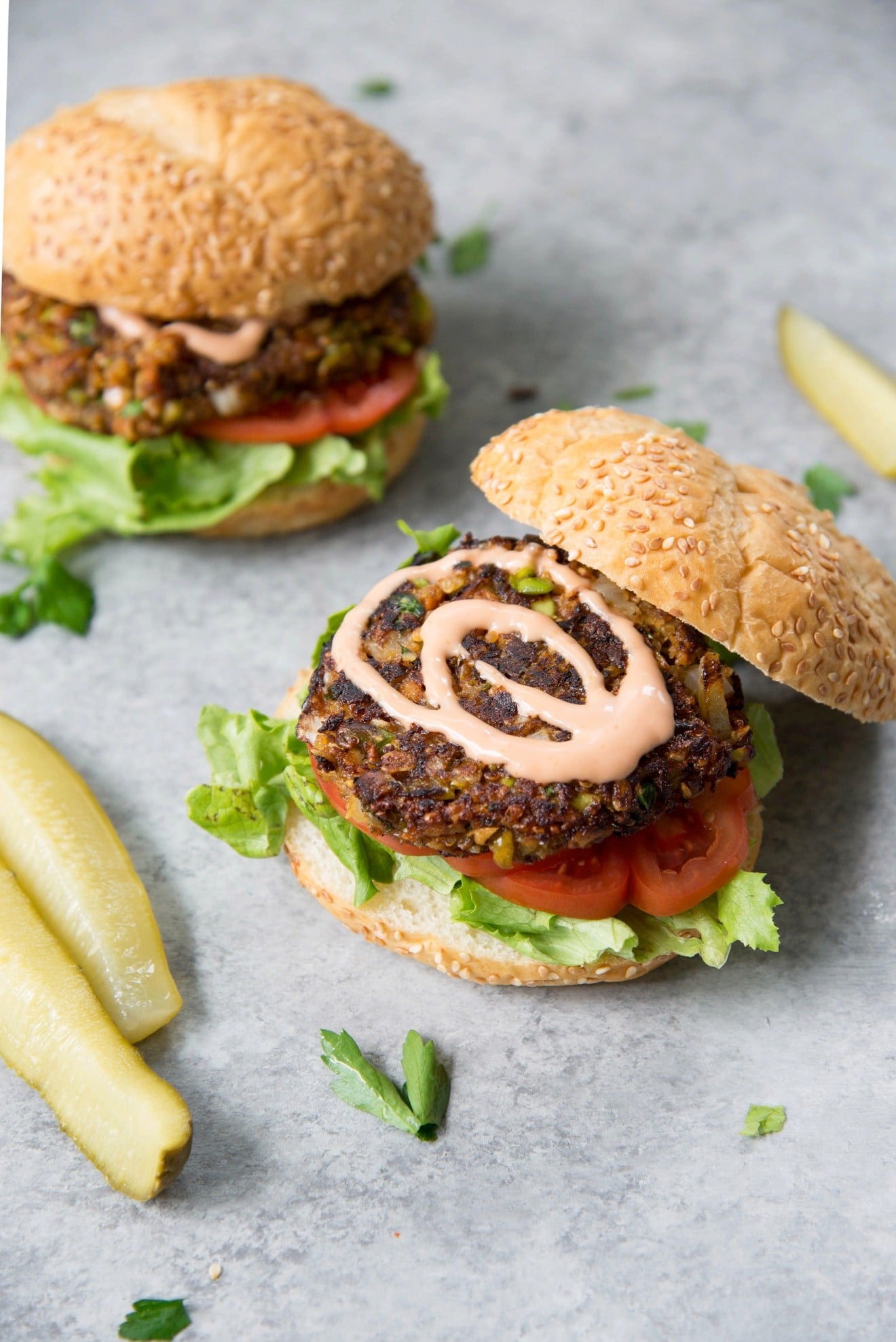 Two edamame grain burgers with lettuce and tomatoes.