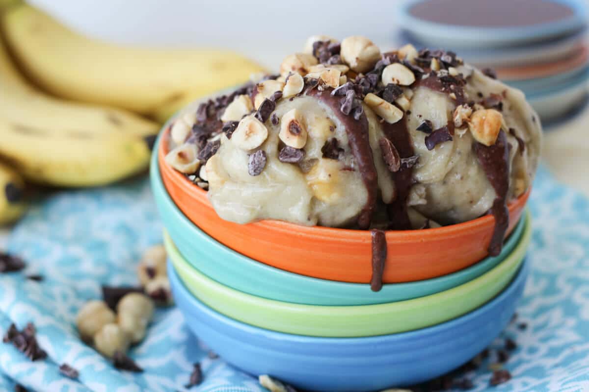 banana and nutella healthy ice cream in an orange bowl topped with chopped hazelnuts