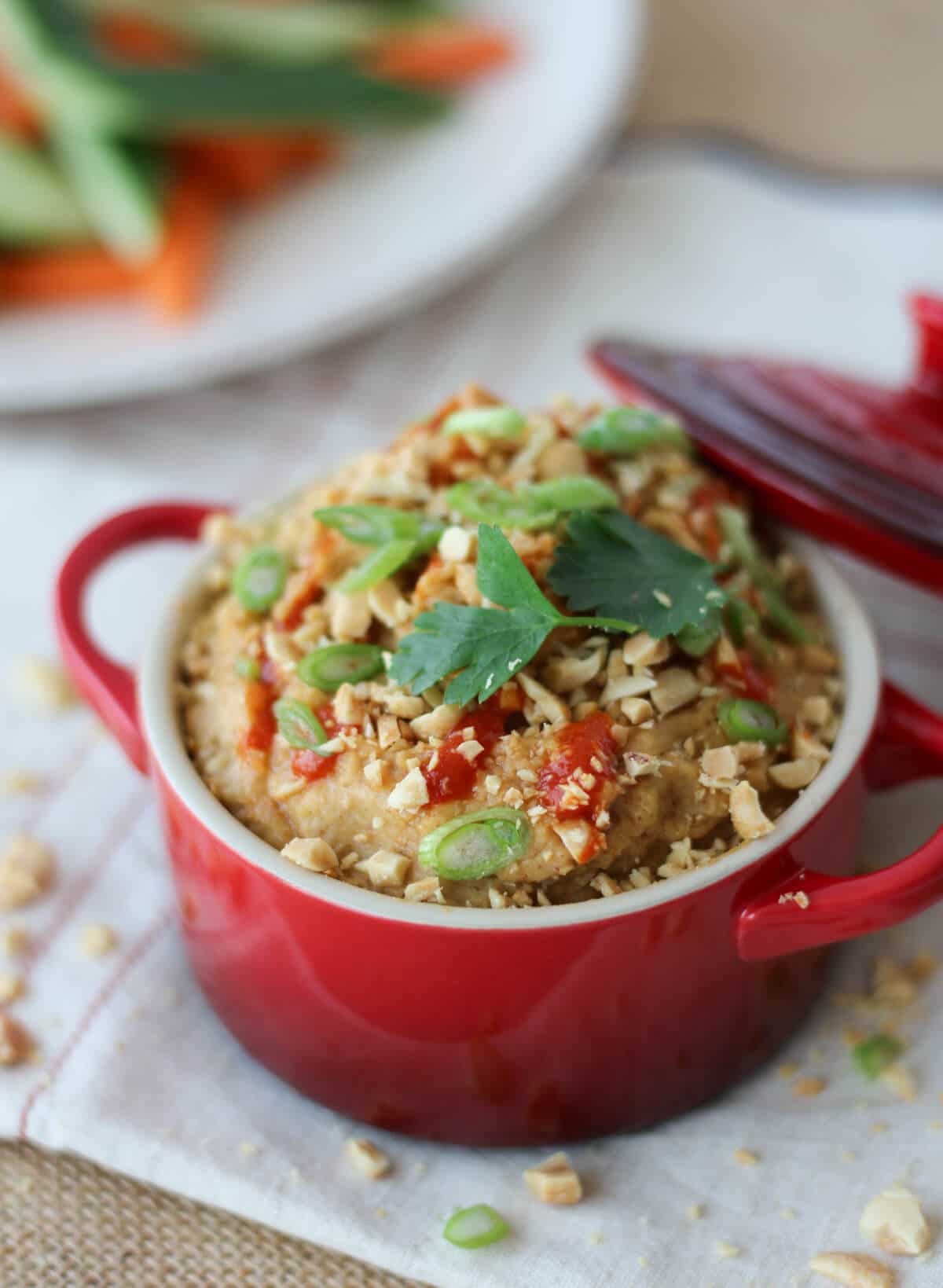 A red bowl containing peanut hummus dip.