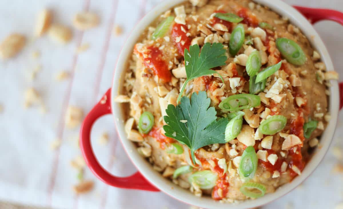 Peanut hummus dip in a red dish.