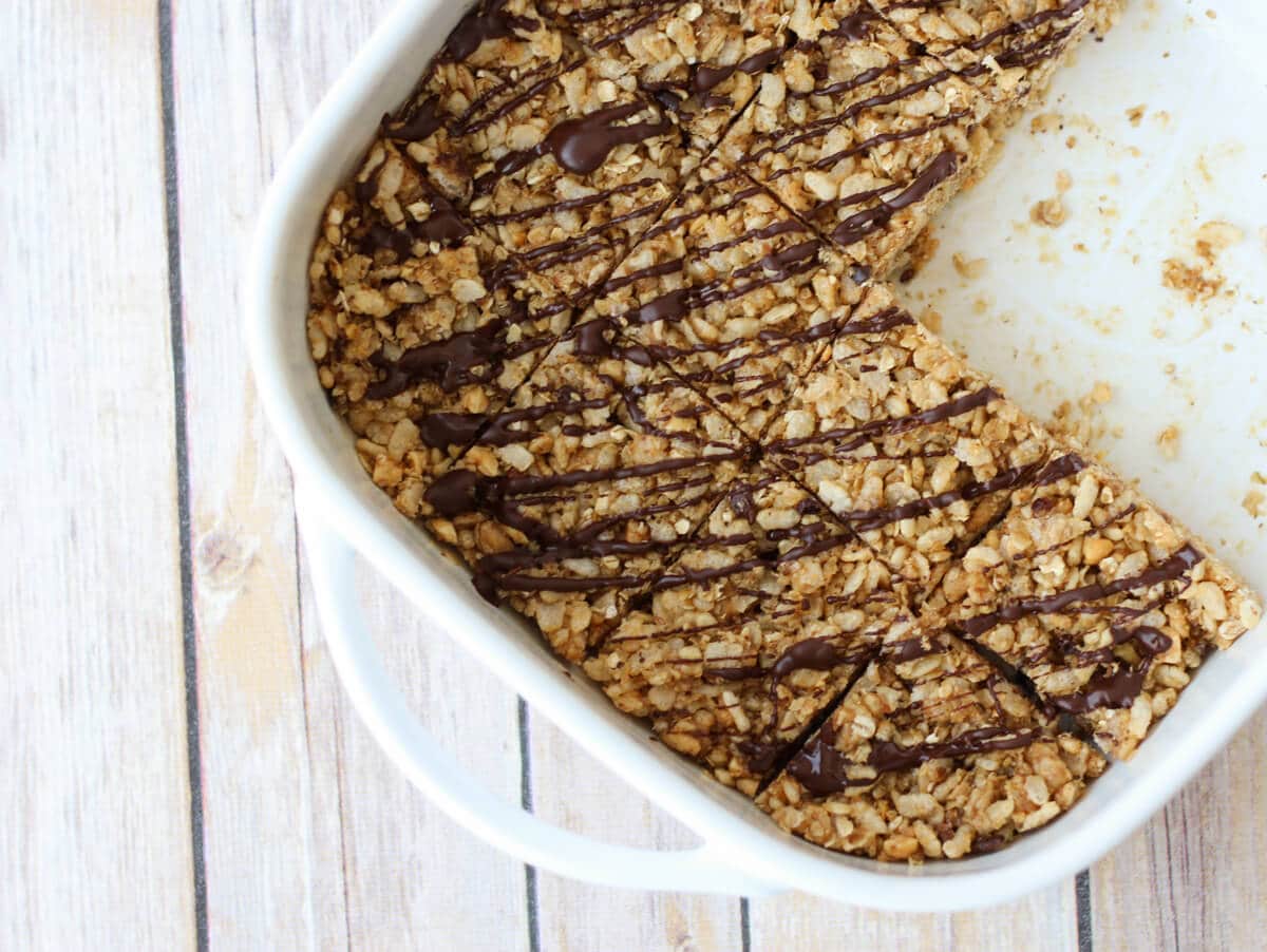 A white baking dish with rice krispie with two slices taken out.