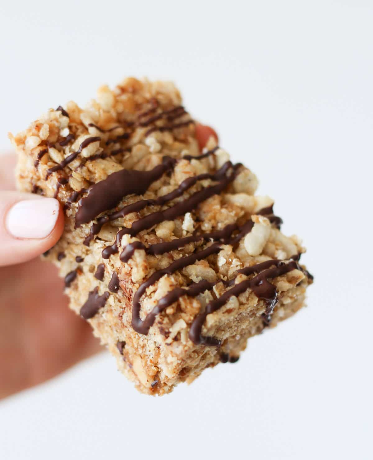 A hand holding a peanut butter rice krispie with chocolate.