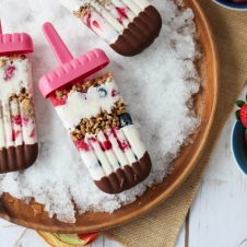 A plate with shaved ice containing multiple banana cream pie berry popsicle with chocolate on top.