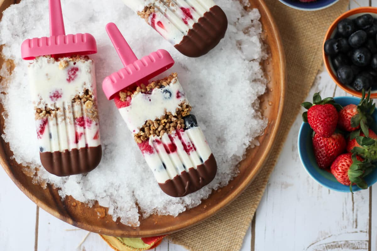 A plate with shaved ice containing multiple banana cream pie berry popsicle with chocolate on top. 