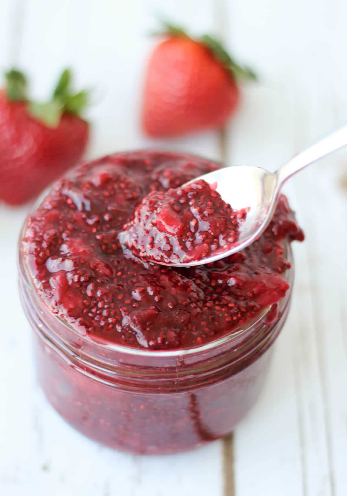 Strawberry chia jam in a jar with a spoon. 