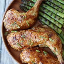 A plate with sliced chicken with grilled asparagus.