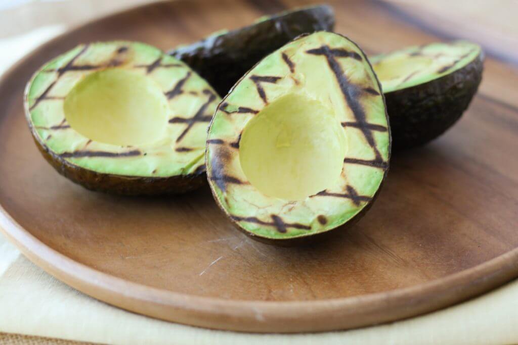 grilled avocado on a wooden plate