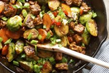 A pan with Brussels sprouts and tempeh stir fry with a spoon inside.