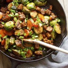 A pan with Brussels sprouts and tempeh stir fry with a spoon inside.