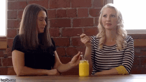 A gif of Abbey Sharp and Abby Langer gagging after tasting food on a spoon.