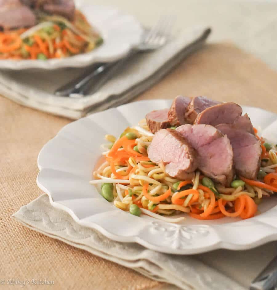 A white plate with zoodles and pork tenderloin on top.