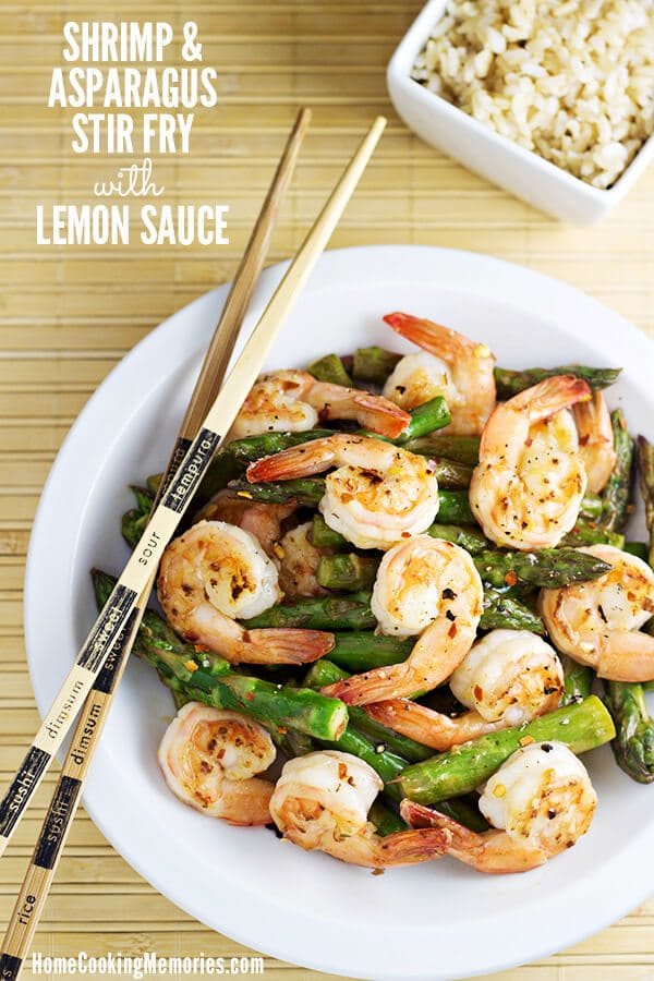 A white plate with shrimp and asparagus stir fry with lemon sauce.