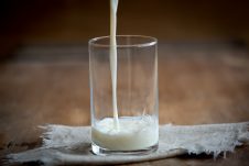 A glass cup with milk being poured in.