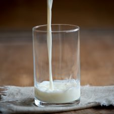 A glass cup with milk being poured in.