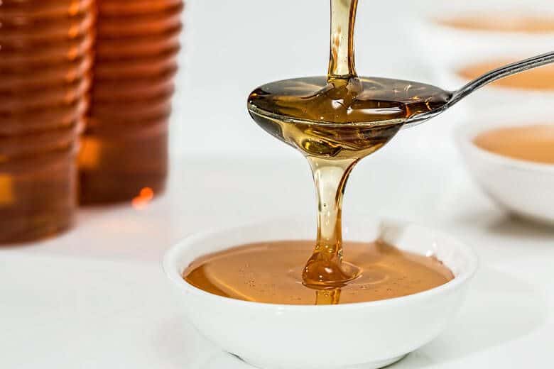 Honey being poured into a white container.