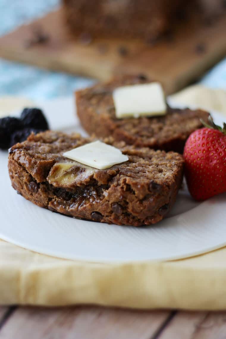 two slices of homemade banana bread on a white plate topped with butter