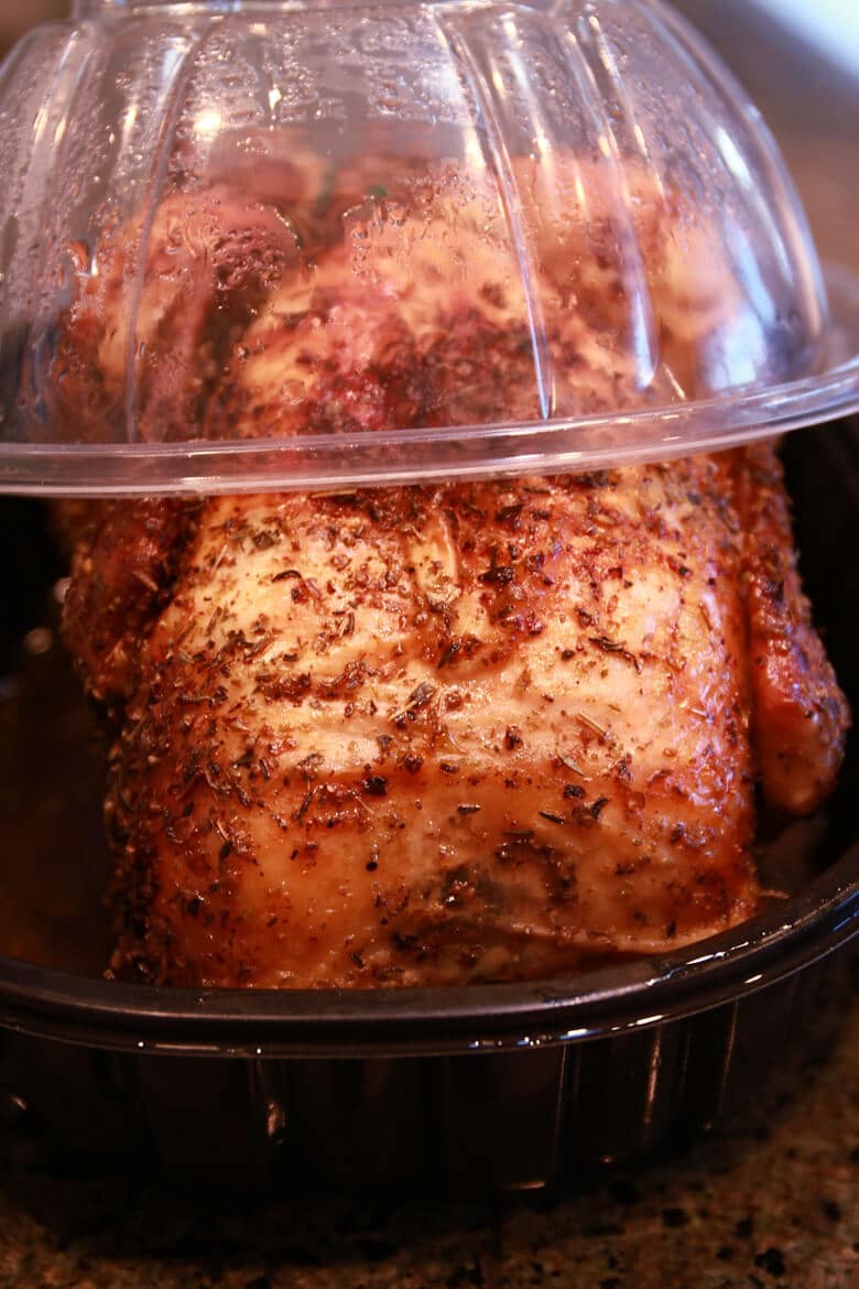 A close up of a rotisserie chicken in its container.