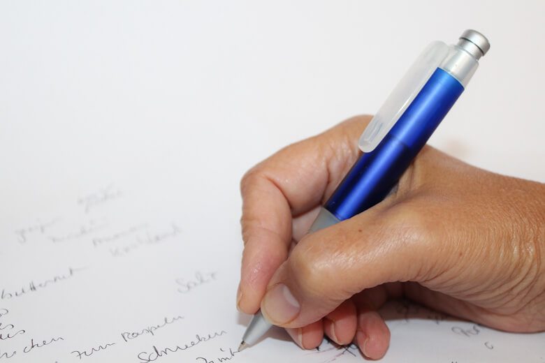 Hand holding a pen writing on paper.