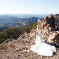 A view of a rocky mountain with Abbey Sharp in a wedding dress standing in front.