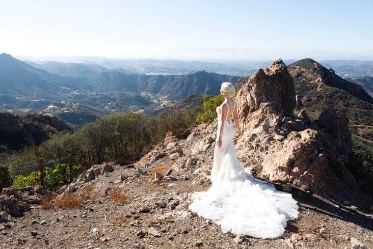 A view of a rocky mountain with Abbey Sharp in a wedding dress standing in front.