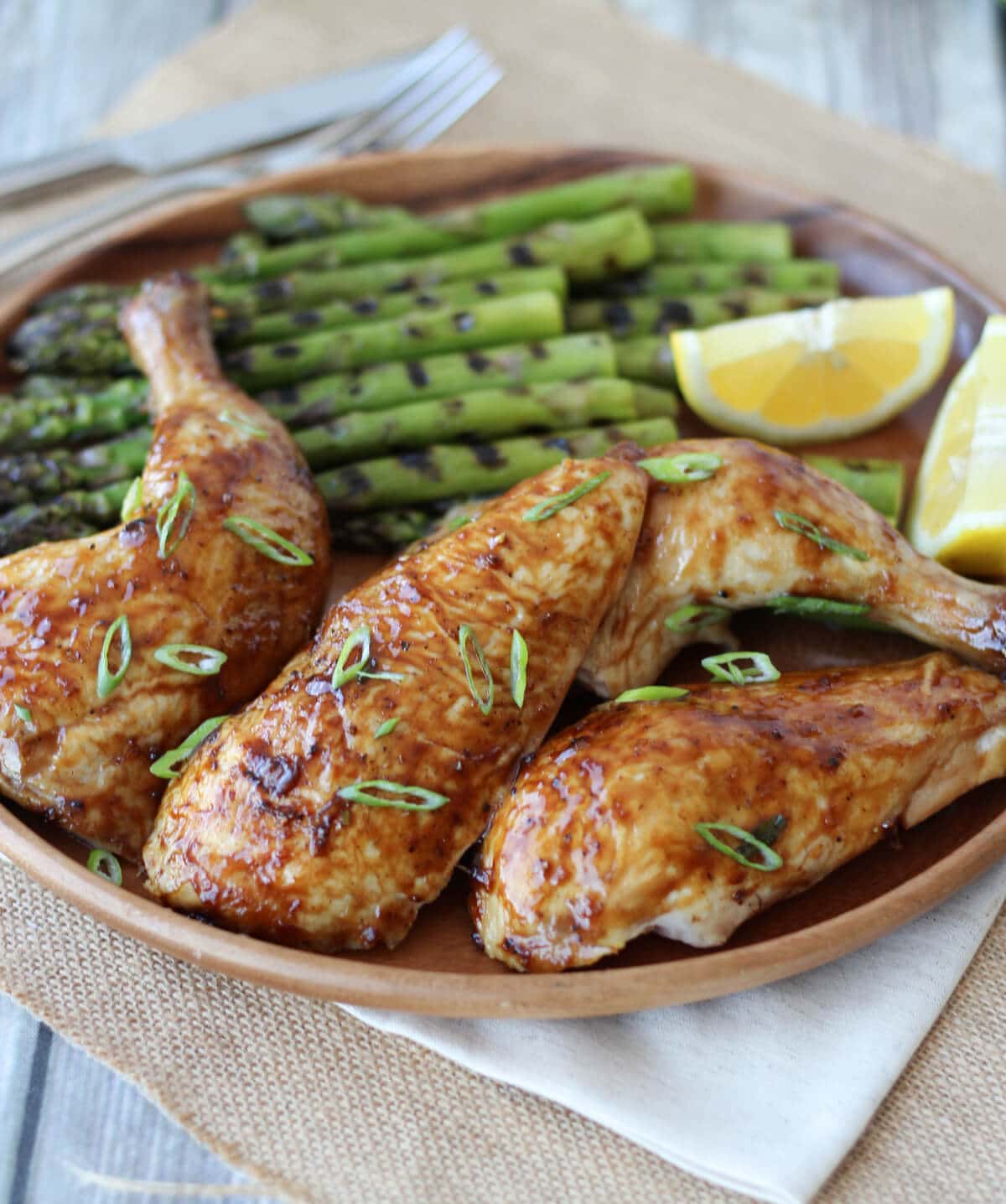 A brown plate with chicken and grilled asparagus.