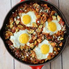 A red skillet containing shaskuka with four eggs.