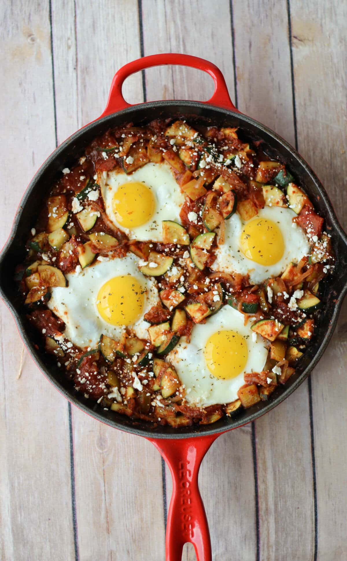 A red skillet containing shaskuka with four eggs.