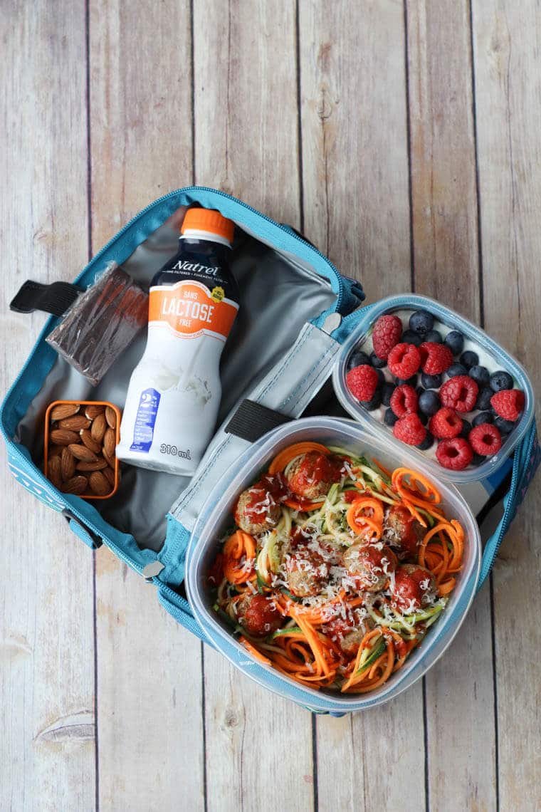 A packed lunch in a lunch bag with a bottle of milk.