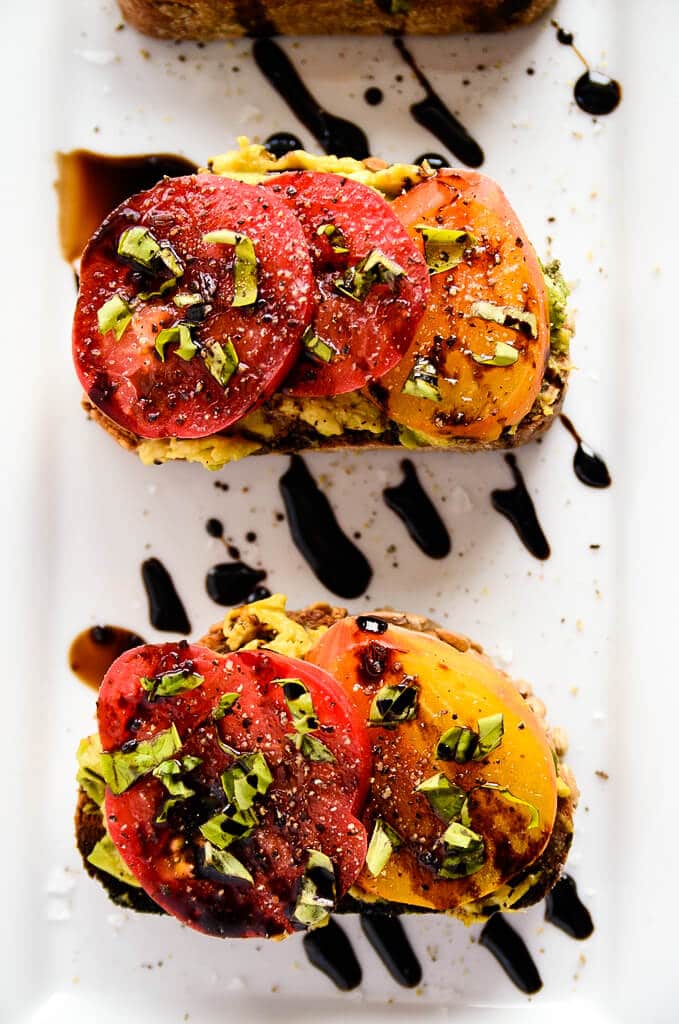 Avocado toast with slices of tomatoes on top with balsamic on top. 