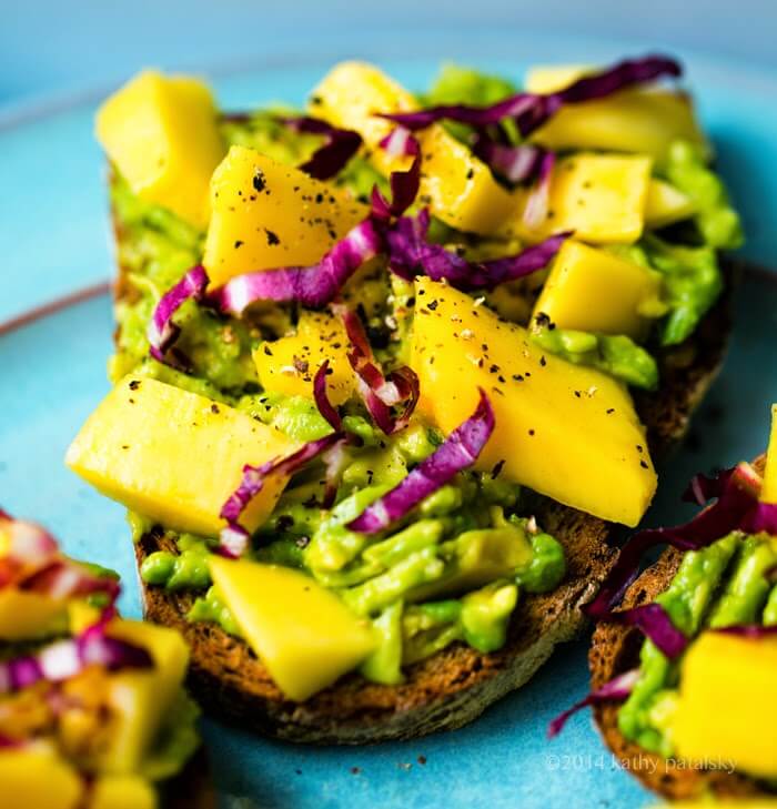 A close up of avocado toast with mango on top.