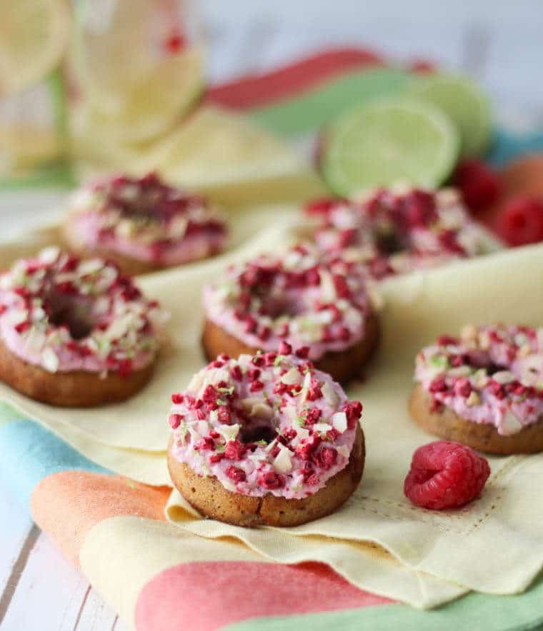 Multiple raspberry margarita donuts on a linen. 