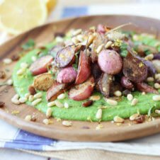 A close up of a plate of za'atar roasted radishes over top of a pea puree.