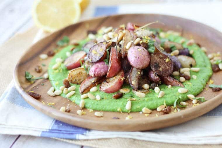 A close up of a plate of za\'atar roasted radishes over top of a pea puree.