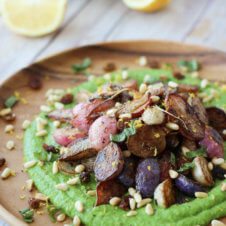 A close up of a plate of za'atar roasted radishes over top of a pea puree.