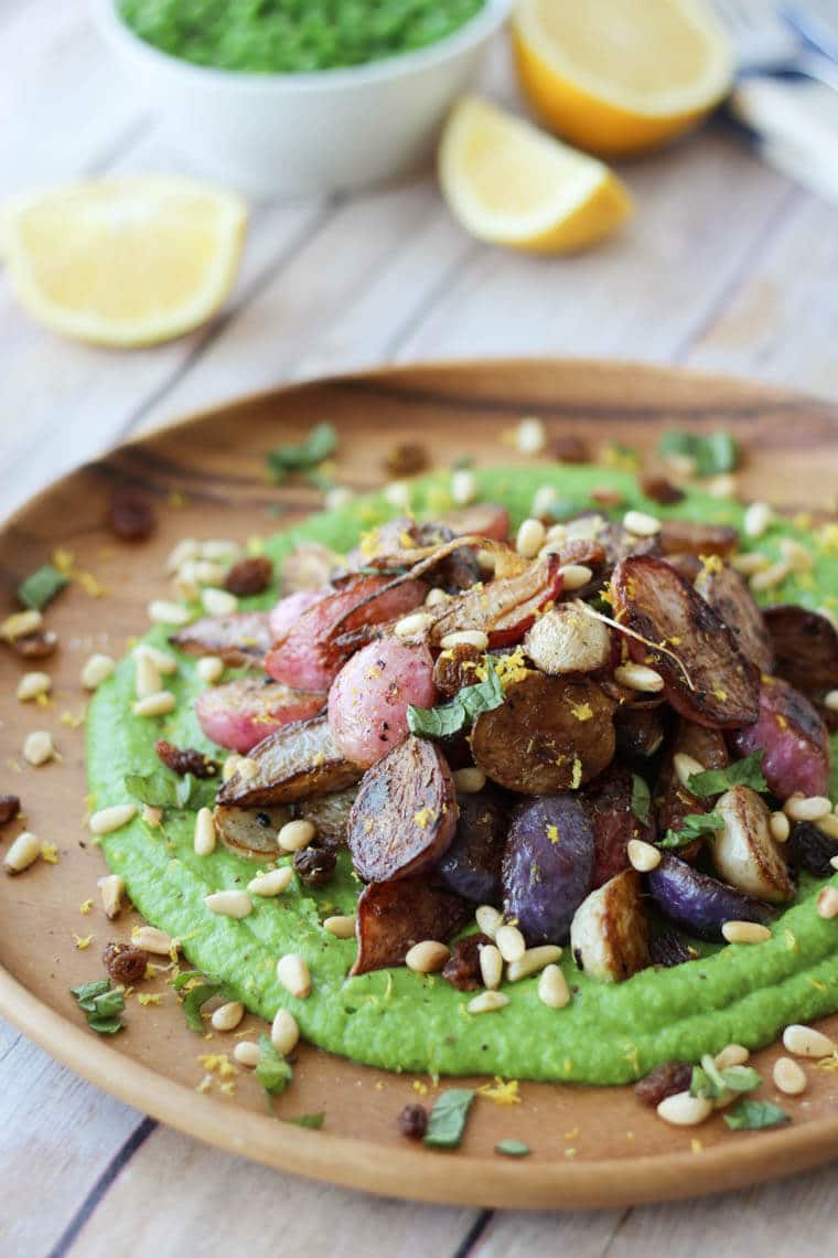 A close up of a plate of za\'atar roasted radishes over top of a pea puree.